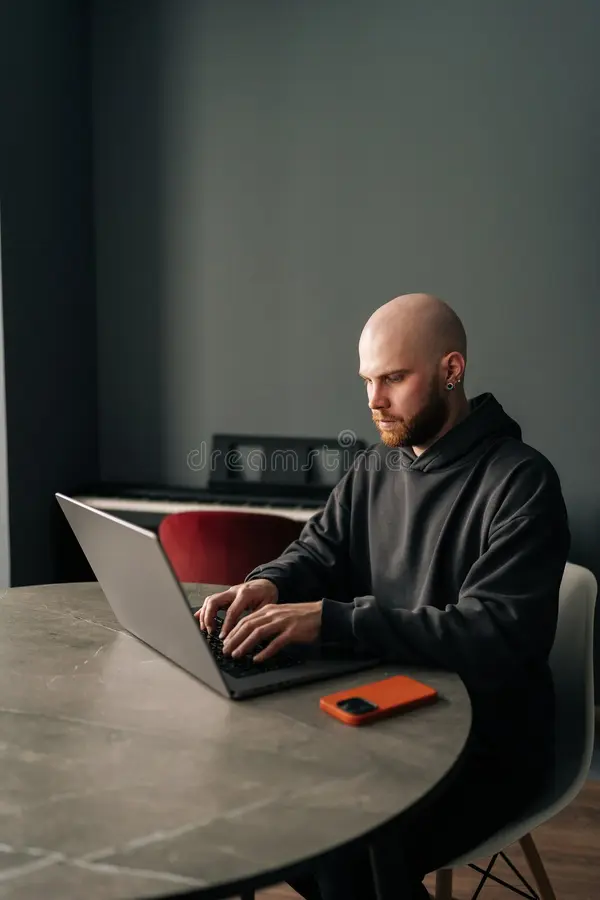 vertical-portrait-young-bald-programmer-beard-ear-piercing-sitting-round-table-home-office-vertical-portrait-370435371